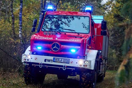 TLF 3000 fährt durch einen Wald mit Blaulicht