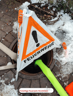 Kanaldeckel mit Feuerwehrschläuchen und Absicherung.