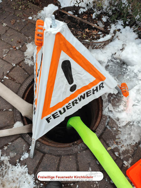 Kanaldeckel mit Feuerwehrschläuchen und Absicherung.
