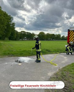 Ein Feuerwehrkamerad löscht einen kleinen Stapel Papier ab.