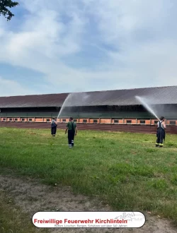 Die Feuerwehrkameraden kühlen mit wasser den Geflügelstall